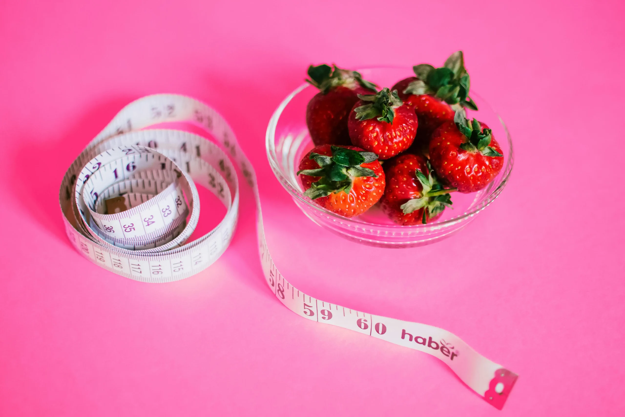 Photo illustrant la perte de poids avec un bol de fraises et un mètre à ruban